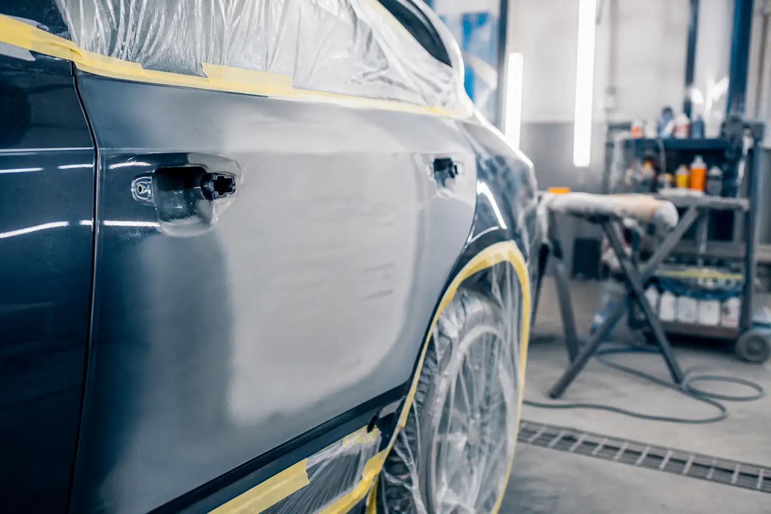 Detalhe de preparo de lataria com mascaramento em oficina automotiva